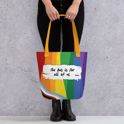 Person holding a rainbow tote bag with text against a gray background